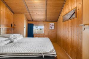 a large bed in a room with wooden walls at FJ1602-Jaegerspris-Strandmarksvej-37 in Jægerspris