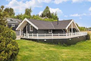 a black house with a white fence in a yard at FJ1602-Jaegerspris-Strandmarksvej-37 in Jægerspris