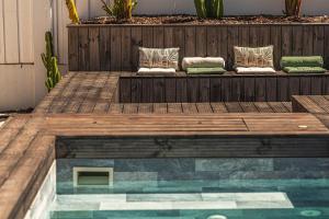 two pillows sitting on a wooden bench next to a pool at Villa Arta by Hostiva in Comporta