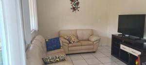 a living room with a couch and a chair and a flat screen tv at Chácara Recanto do Sossego in Araçoiaba da Serra
