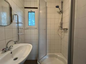 a white bathroom with a shower and a sink at Boslodge 7 personen in Tiendeveen