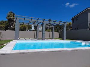 a swimming pool with a pergola next to a building at My Plett, Your Plett in Plettenberg Bay