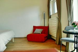 a room with a red chair and a bed at La Boutique in Saignelégier