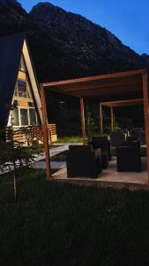 a group of chairs sitting under a pavilion in front of a house at Arditi's Chalets in Bogë