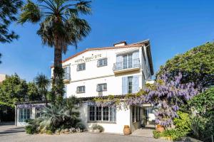a white building with a palm tree and purple flowers at Hôtel Beau Site - Cap d'Antibes in Antibes