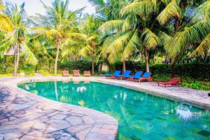 a swimming pool with blue chairs and palm trees at Jumbo Art S Villas in Diani Beach
