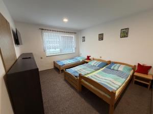 a bedroom with two beds and a desk and a window at Penzion Hedvika in Kravaře