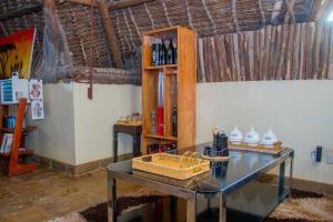 a room with a table and a shelf of wine bottles at Jumbo Art S Villas in Diani Beach