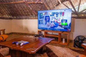 a living room with a large flat screen tv on a table at Jumbo Art S Villas in Diani Beach