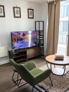 a living room with a tv and a green chair and a table at Cozy One bedroom with Free Underground parking in Mailbox Birmingham city in Birmingham