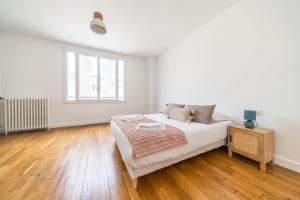 a white bedroom with a bed and a wooden floor at Le Balcon Gaillard in Brive-la-Gaillarde