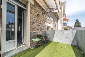 a patio with a table and a chair next to a building at Le Balcon Gaillard in Brive-la-Gaillarde