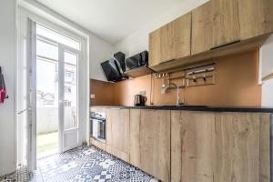 a kitchen with wooden cabinets and a large window at Le Balcon Gaillard in Brive-la-Gaillarde