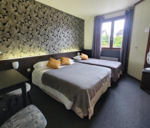 a hotel room with two beds and a window at Logis Hôtel Le Merle Blanc in Digoin