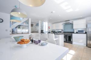 a white kitchen with a plate of food on a table at The Cowshed in Truro
