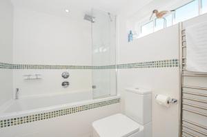 a white bathroom with a tub and a toilet at The Cowshed in Truro +38 photos