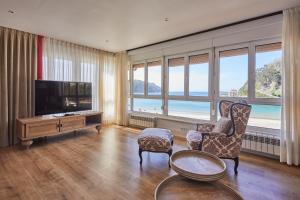 a living room with a tv and a couch and chairs at Silken Gran Hotel del Sella in Ribadesella