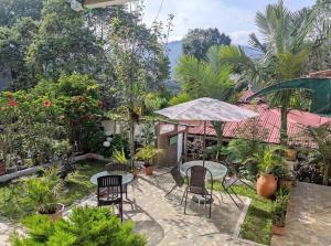 a patio with tables and chairs in a garden at Hostal Vistaguila in Salento