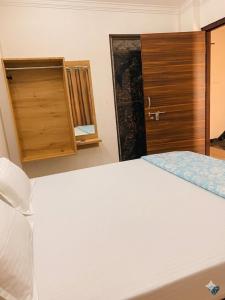 a bedroom with a white bed and a wooden door at Baloon Rooms Taramandal in Gorakhpur +2 photos