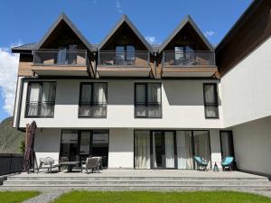 a building with a balcony with chairs and a table at Oli Home in Kazbegi