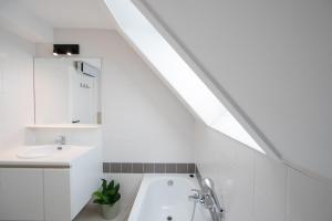 a white bathroom with a sink and a bath tub at Cozy apartment with a great location at "Residentie GAUGUIN" in Nieuwpoort