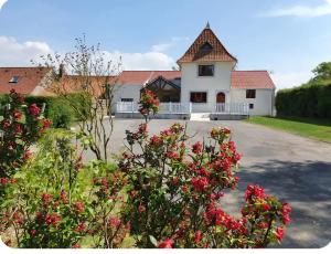 a white house with red flowers in front of it at La Cantraigne in Audembert