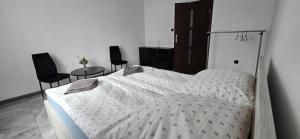 ein weißes Bett in einem Zimmer mit zwei Stühlen in der Unterkunft Jarocin in Jarocin