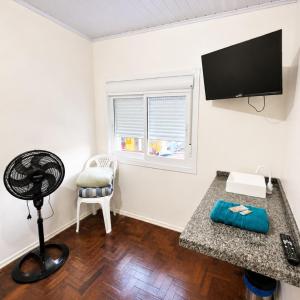 a room with a desk with a fan and a window at Hotel Presidente Ibirubá in Ibirubá