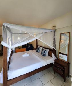 a bedroom with a canopy bed and a mirror at Beachfront Studio in Diani Beach