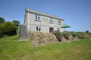 a house with a stone wall and an umbrella at 3 Bed in Padstow oc-treba in Saint Merryn