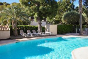 a swimming pool with two chairs and palm trees at Hôtel Beau Site - Cap d'Antibes in Antibes