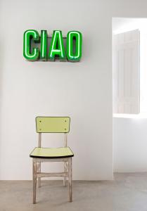 a chair in front of a wall with a sign at Pensão Agrícola in Cabanas de Tavira