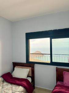 a bedroom with two beds and a large window at Harmony immo in Bir el Djir
