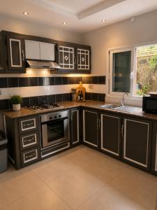 a kitchen with dark brown cabinets and a sink at ARIEL BEACH VILLA* in Grand-Baie