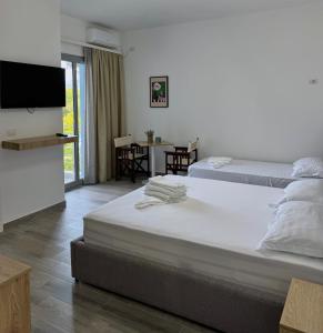 a bedroom with two beds and a flat screen tv at River Residence in Orikum