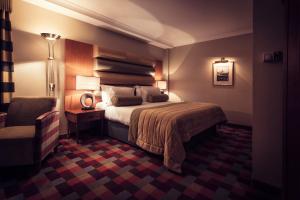 a hotel room with a bed and a chair at Carlton George Hotel in Glasgow