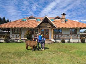 a group of people standing in front of a house with a cow at Rumipaxi Lodge in Latacunga