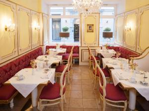 a restaurant with tables and chairs and a chandelier at Schlosshotel Römischer Kaiser in Vienna