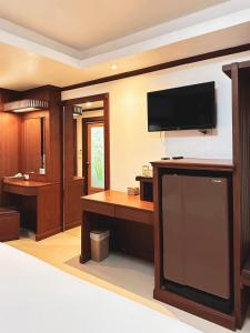 a living room with a tv and a desk with a television at บ้านเกื้อ เดอะ ลิฟวิ่ง in Nakhon Ratchasima