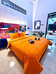 a bedroom with a large orange bed with two mice on it at HHHH Hostel in Banyuwangi