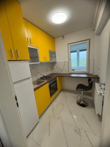 a kitchen with yellow cabinets and a chair in it at Studio Militari Residence - MR1 in Chiajna