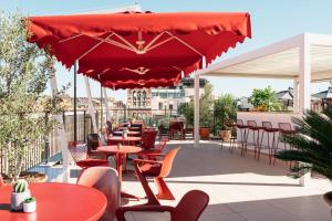 a patio with tables and chairs and a red umbrella at Ruby Lilou Hotel Marseille by IHG in Marseille +35 photos
