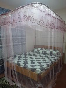 a bed with a canopy with a checkeredkered bedsheet at Royal guest home in Mokowe