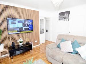 a living room with a couch and a flat screen tv at Luxurious & Spacious 5 Bedroom Property in Belvedere