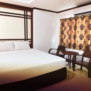 a bedroom with a bed and a chair and a window at บ้านเกื้อ เดอะ ลิฟวิ่ง in Nakhon Ratchasima