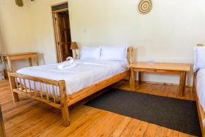 a bedroom with a large bed and a table at Riverside Gorilla Lodge - Bwindi in Kinkizi