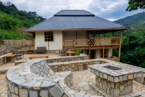 a house with a stone patio and a building at Riverside Gorilla Lodge - Bwindi in Kinkizi