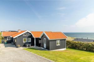a black house with an orange roof next to the ocean at G308-Lemvig-Violvej-108 in Lemvig