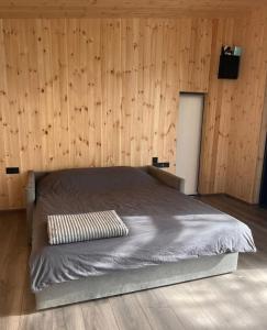 a bed in a room with a wooden wall at Sevan Resort No5 in Chʼkalovka