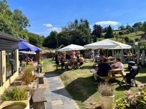 a group of people sitting in the grass under umbrellas at The Farmers Boy Inn Guest House in Longhope